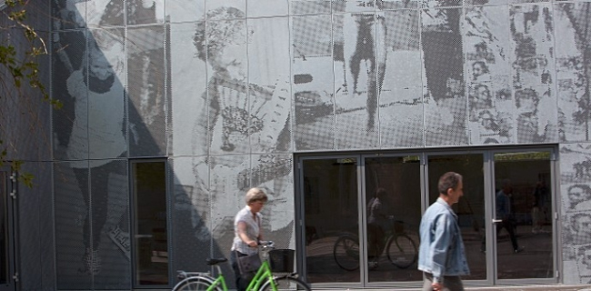 Перфорация на фасаде музыкальной школы в городе Nørresundby в Дании создает рисунок, изображающий поющих, играющих и танцующих детей. Проект разработан архитекторами Kærsgaard  Andersen A/S. 32 листа горячего цинкования (RMIG), сталь толщиной 2 мм, общая площадь 6х10 метров. Фотография Rmig.