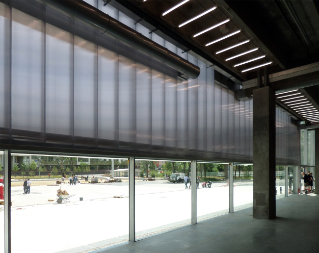 The polycarbonate facade starts two meters up from the ground. The concrete floor of the foyer is the same level with the outside ground. Photograph © Ilia Mukosey
