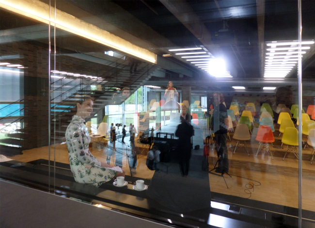 Rem Koolhaas (behind the glass) gives an interview on the day of the inauguration of the new building of the "Garage". Photograph  Ilia Mukosey