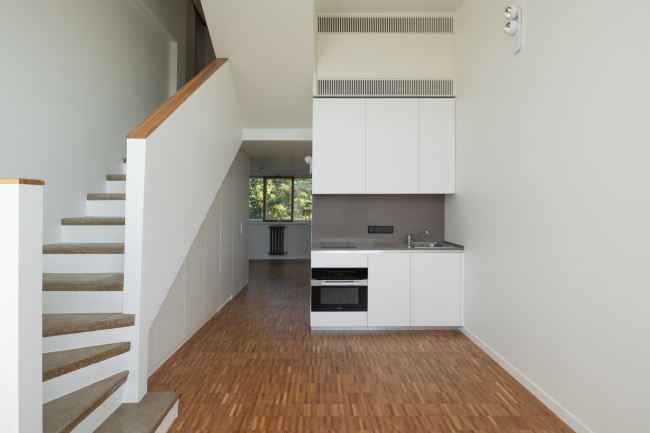 The interior of the living room with a kitche area an F-type cell. The stair coverage is made of xylolite with sawdust used as filler. Restoration and adaptaion of the the cultural heritage site Narkomfin Building (2017-2020)