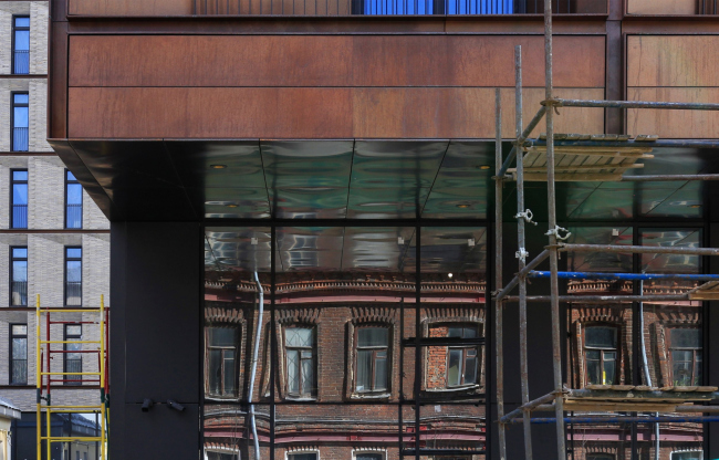 Reflection of the house to the east from the complex in the glass of the 1st floor. The housing complex "Medny 3.14"