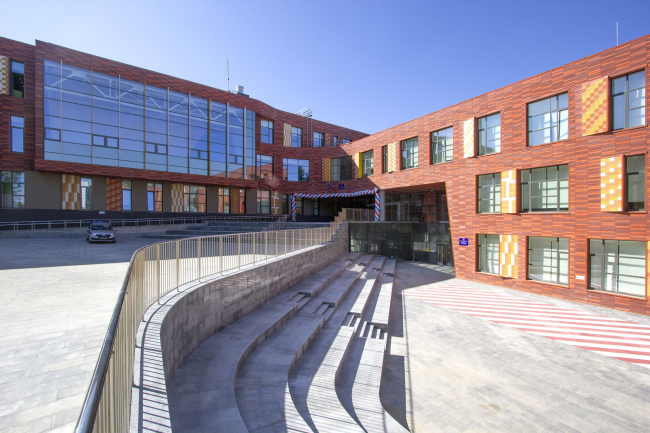 An outdoor amphitheater in front of the school entrance. The separated entrances to the junior (bottom) and senior (top) schools are clearly visible